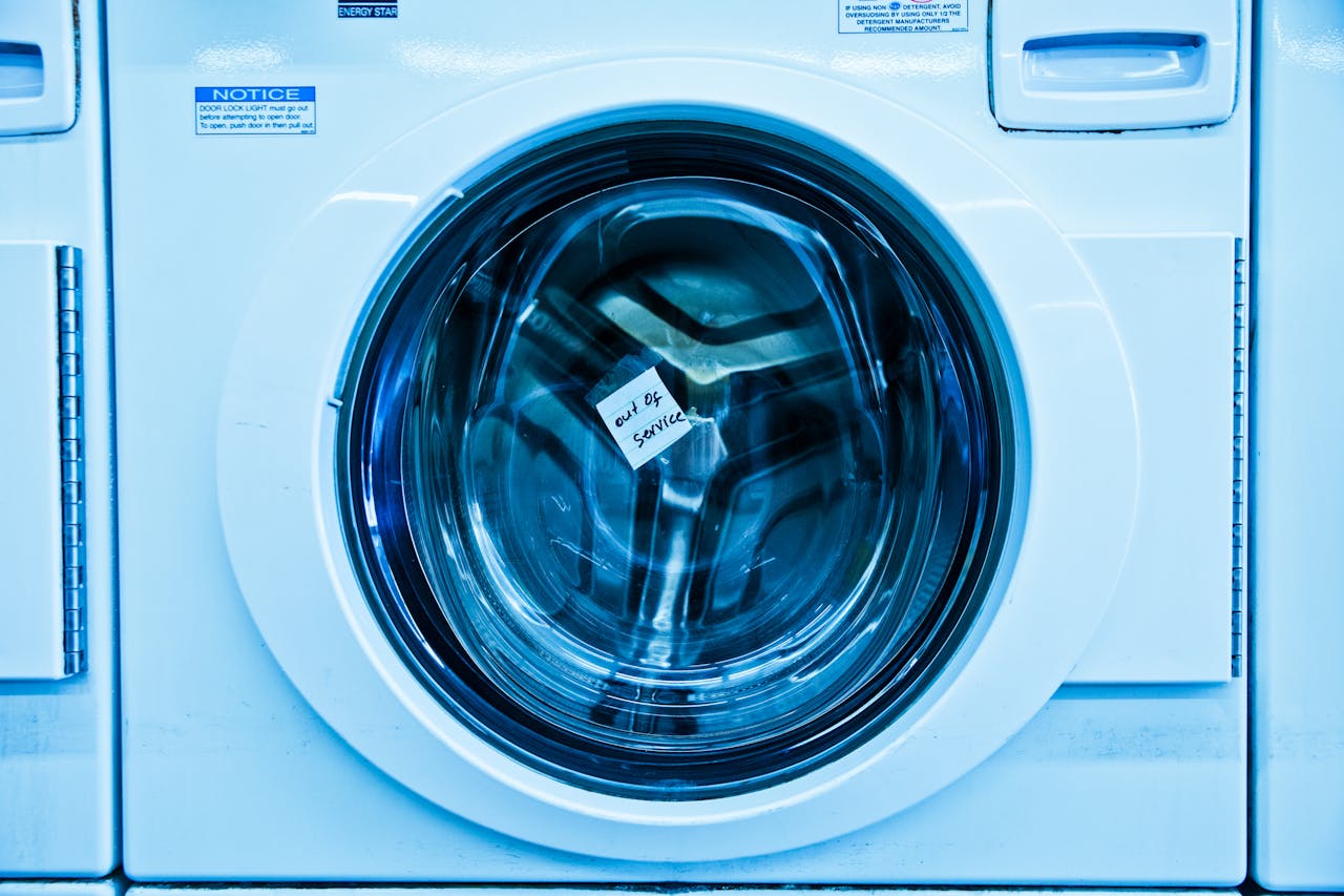 pexels-photo-4700389 Close-up of an out-of-service washing machine in a laundromat with a blue tint.